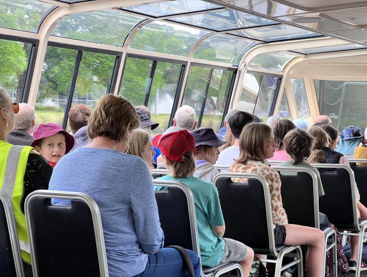 Students seated and looking out the windows of the ferry cabin